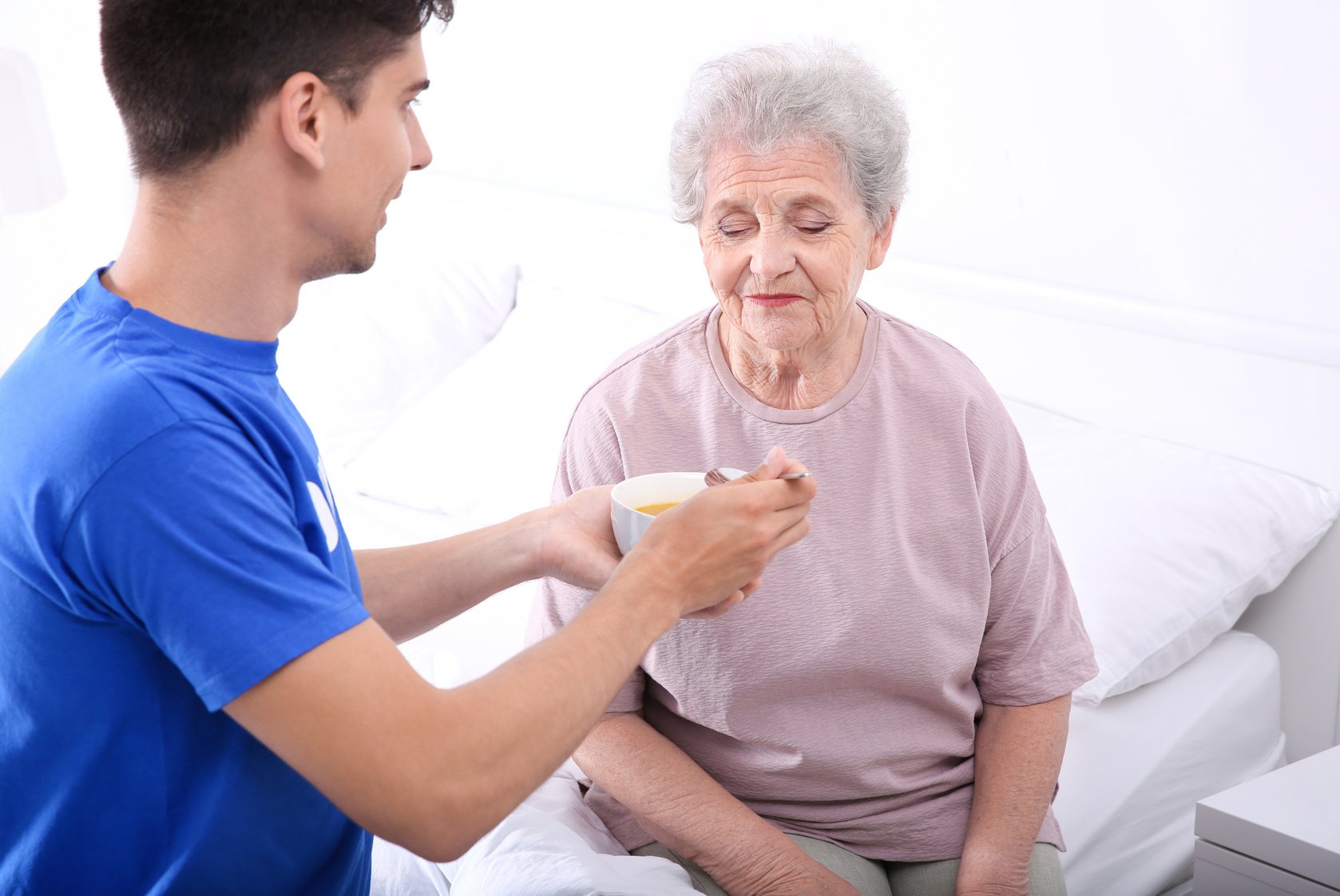 Male Volunteer Feeding Elderly Woman 